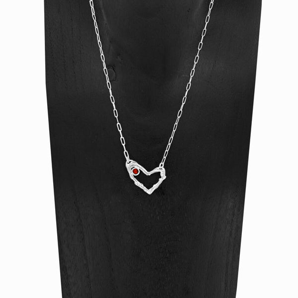 Close-up of Coragem Heart Necklace with Garnet gemstone, set in sterling silver heart design by Elke Van Dyke Design.
