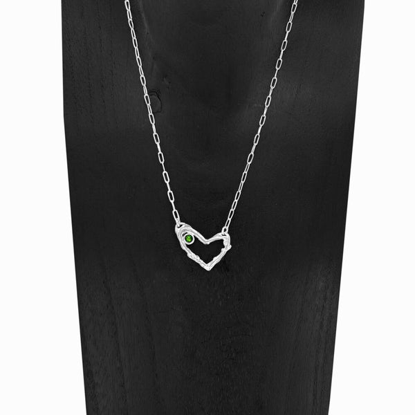 Close-up of Coragem Heart Necklace with Garnet gemstone, set in sterling silver heart design by Elke Van Dyke Design.