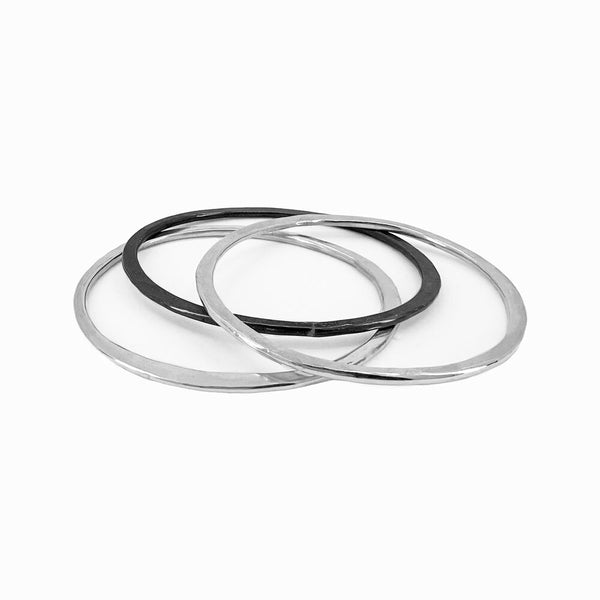 Set of three sculptural sterling silver bangles. Lightweight, hand-formed stacking bracelets by Elke Van Dyke, crafted for daily wear.