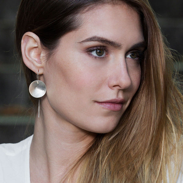 Handcrafted Silver Moon Earrings – minimalist lunar jewelry by Elke Van Dyke with celestial, organic elegance. Concave shape. Brushed finish.