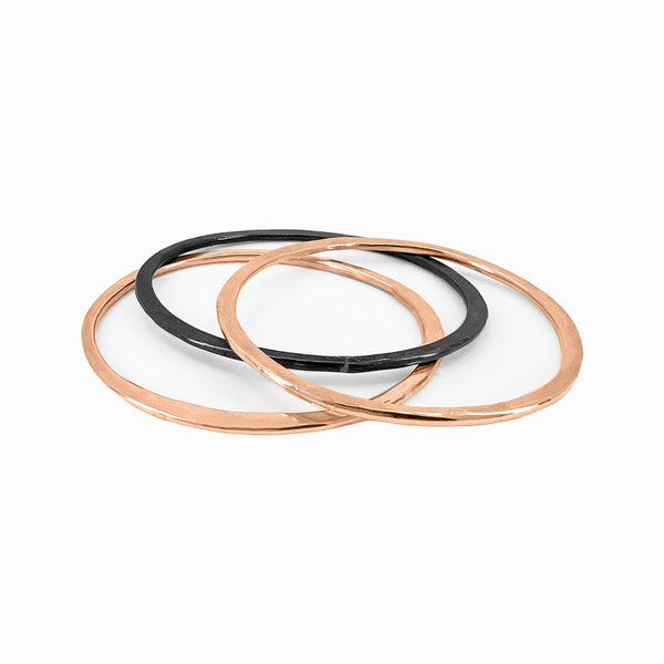 Orbit bangle set in rose-gold, gold, and silver—hand-forged stacking bracelets with sculptural form by Elke Van Dyke.