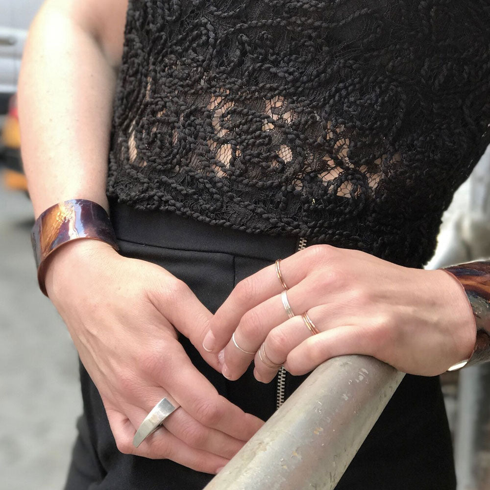 Elke Van Dyke Design Gold Stacking Ring Set on model's hand holding a rail